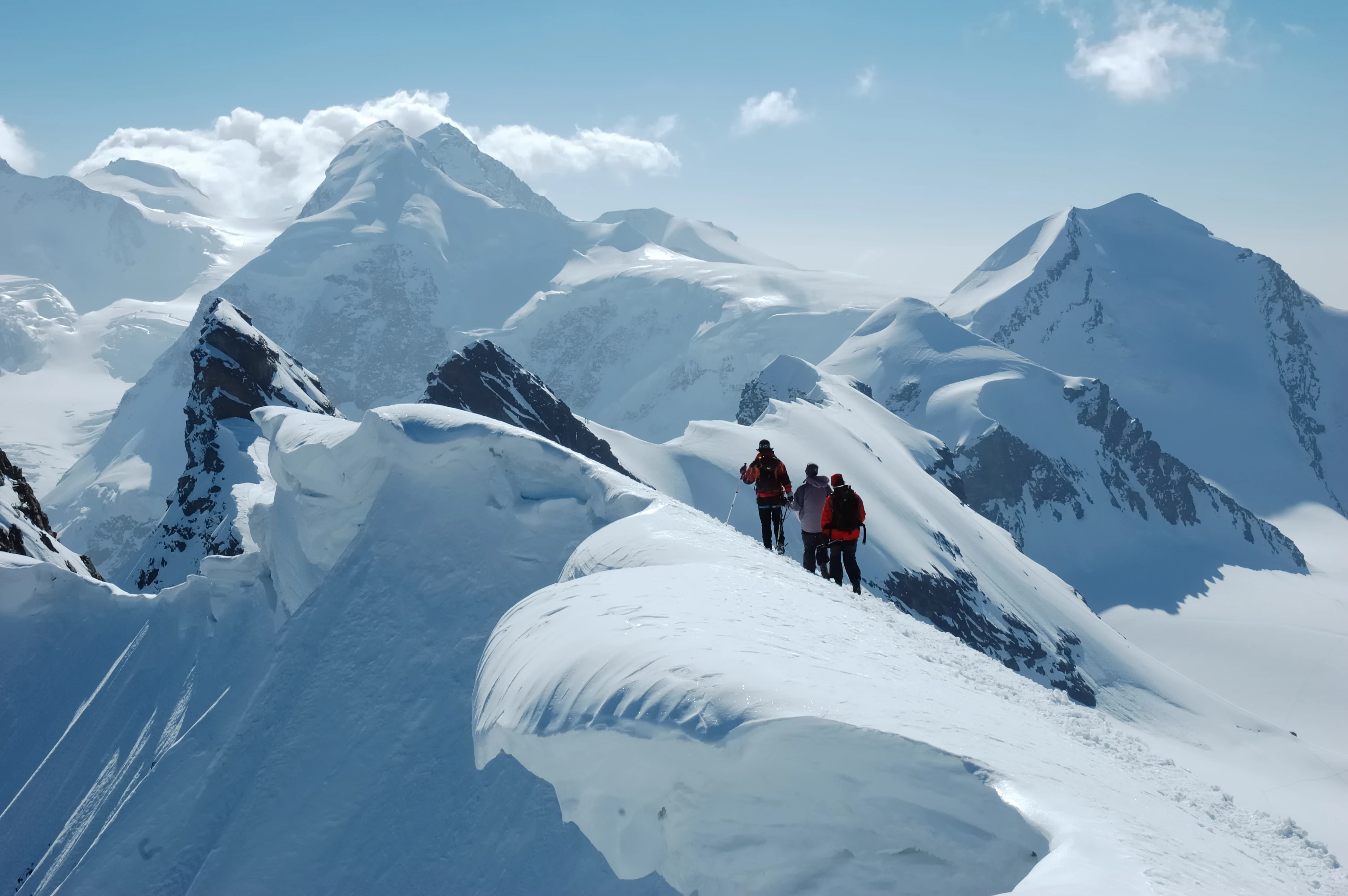 Dramatische Weitwinkel-Aufnahme einer Wandergruppe beim Erreichen eines alpinen Gipfels